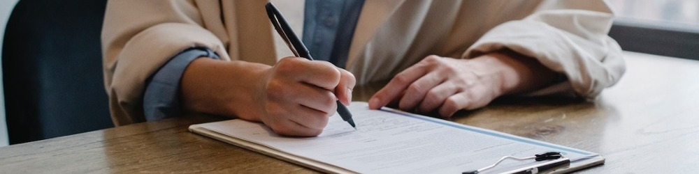 close up of hand writing on clipboard