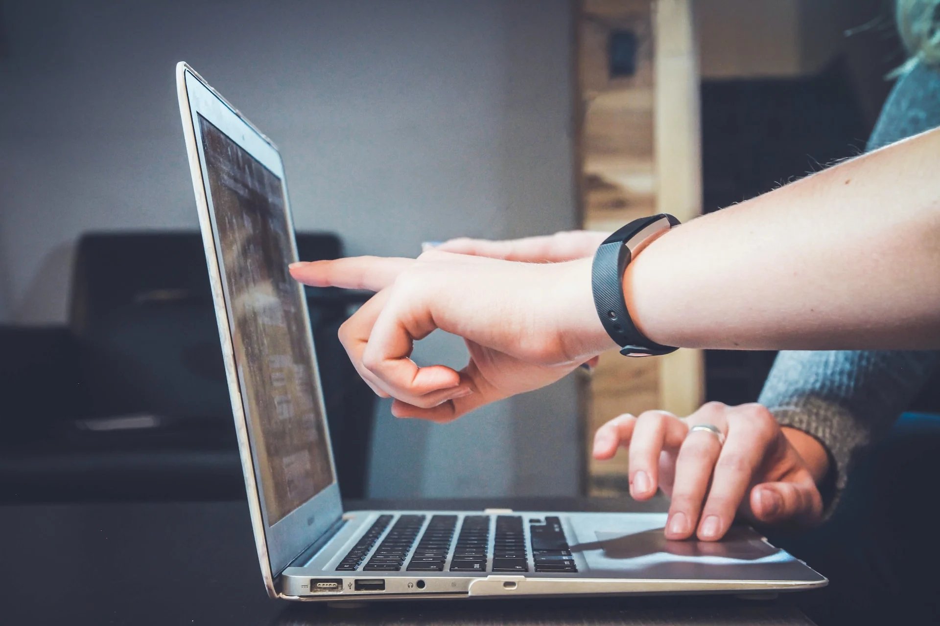 Person pointing at a laptop screen.