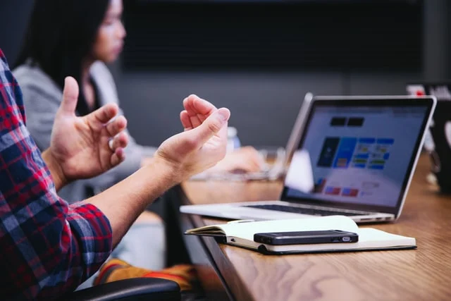 A person sitting in a conference room looking at their laptop.