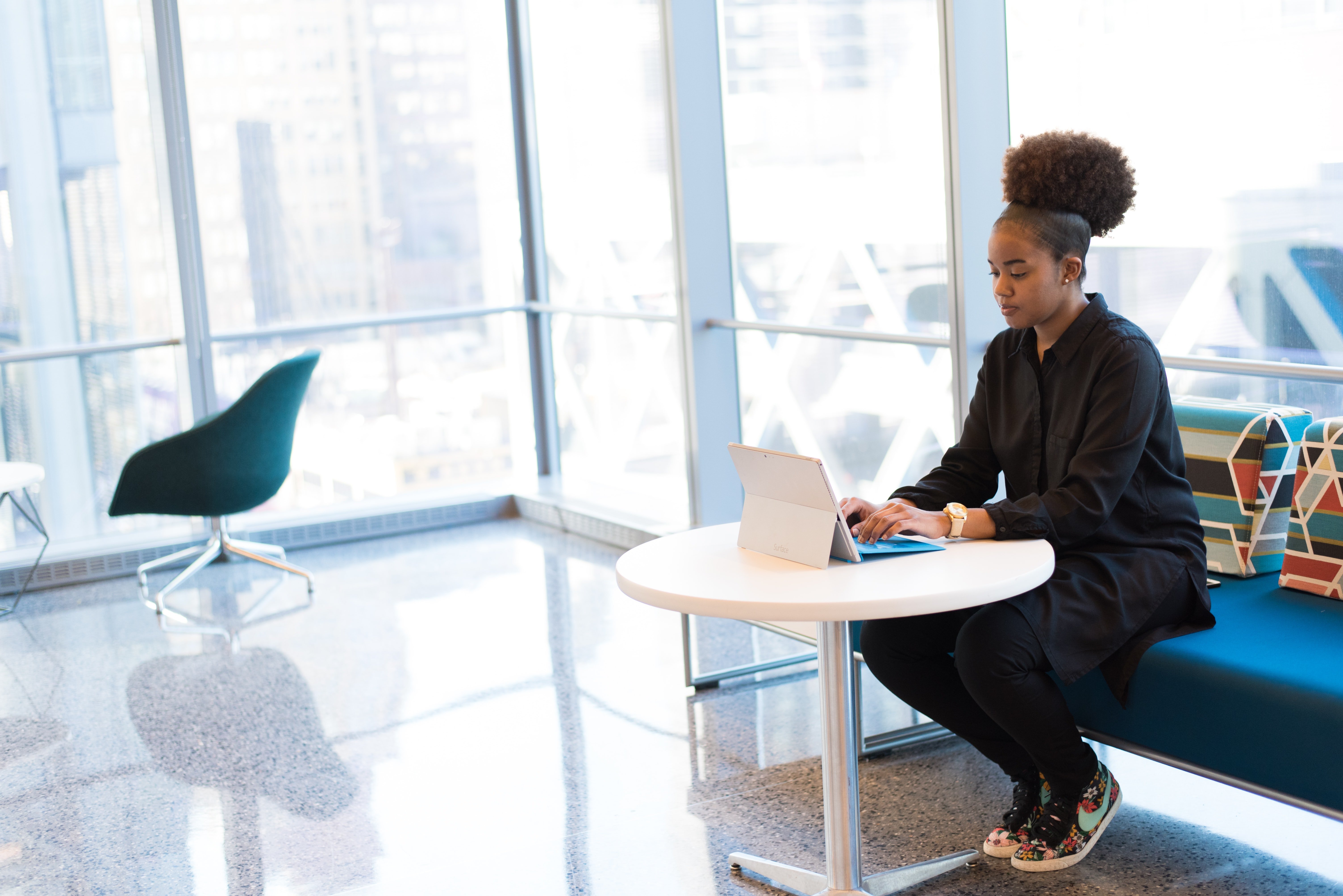 a black woman sitting at a small white table with a tablet