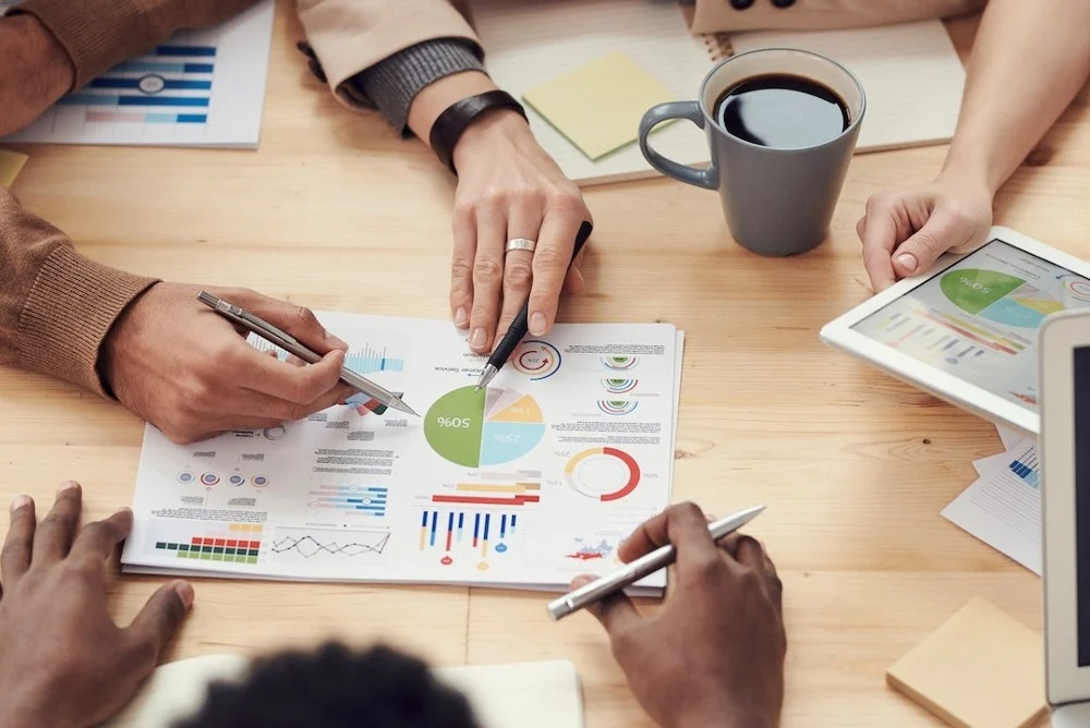 Group of people analyzing a piece of paper that has various graphs.