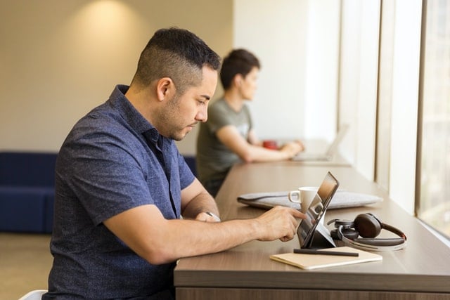 A man sitting at a table using his iPad to access the student information management system. 