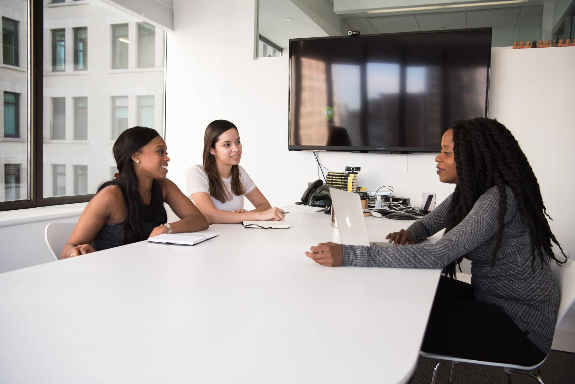 Three people sitting at a table in a conference room. 